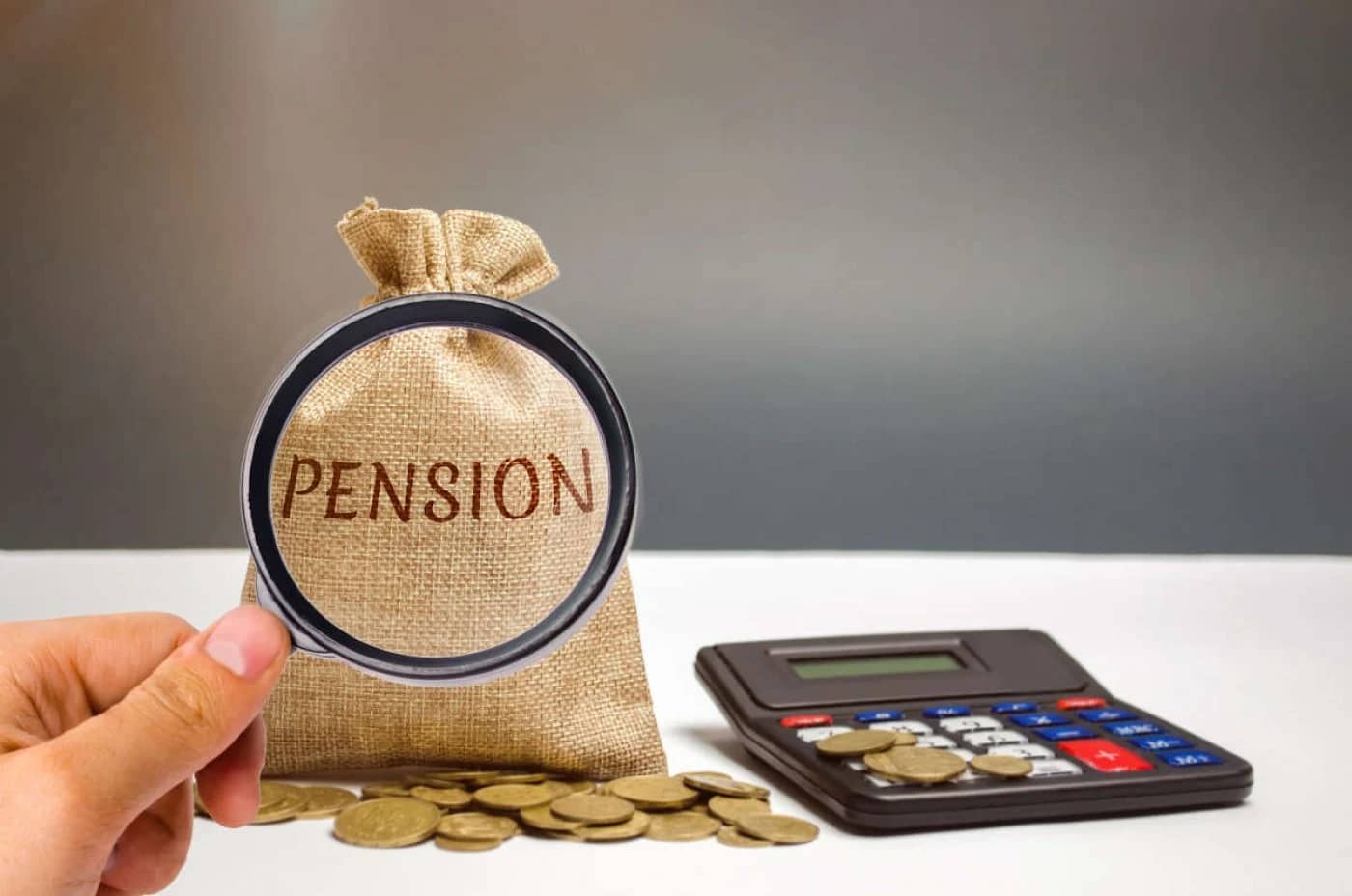 Lupa pusă pe un săculeţ pe care scrie Pension lângă un calculator şi câteva monede