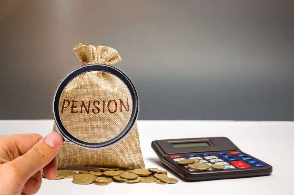 Lupa pusă pe un  săculeţ pe care scrie Pension lângă un calculator şi câteva monede