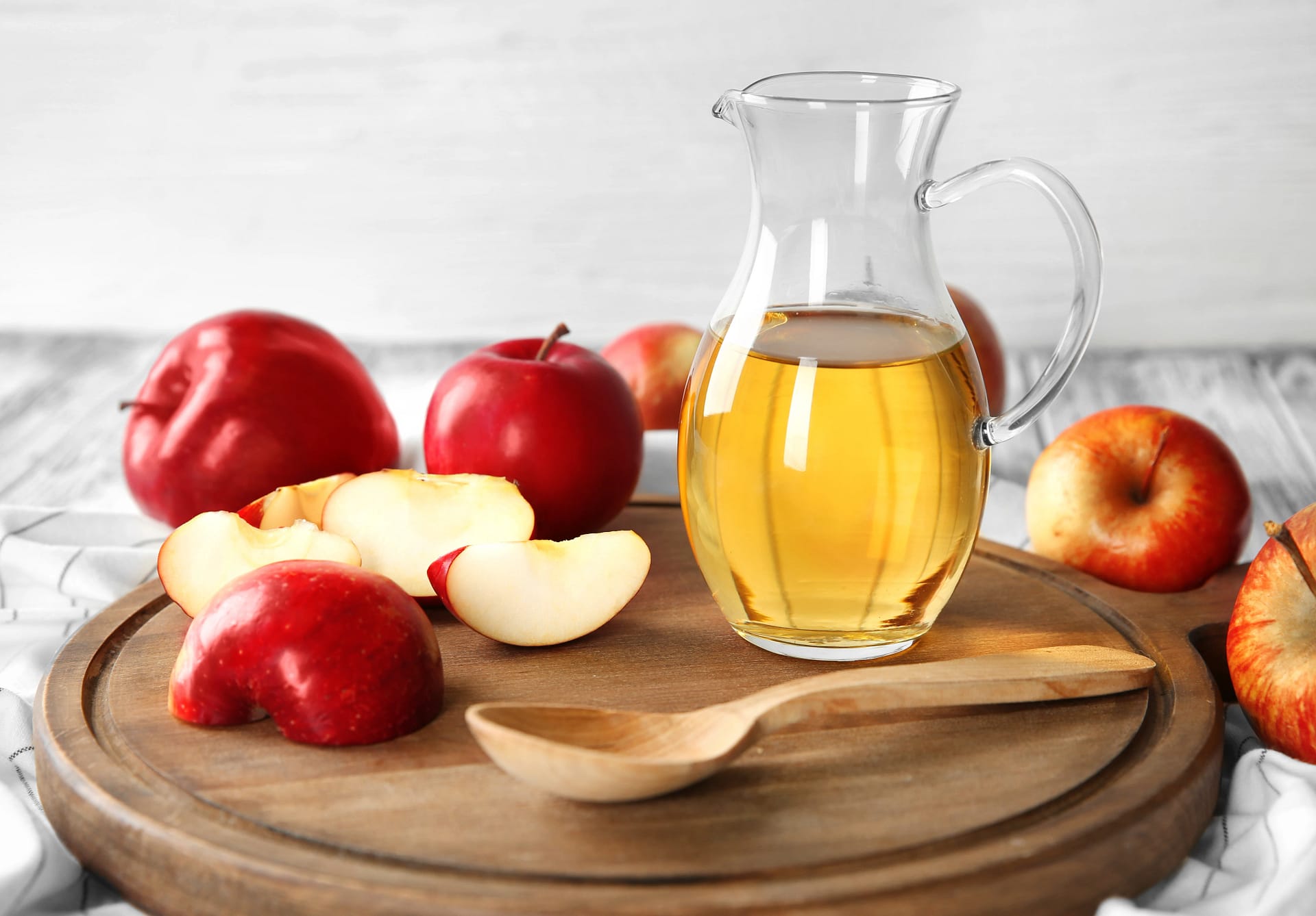 O carafă cu oțet înconjurată de mere tăiate sau întregi Foto Shutterstock