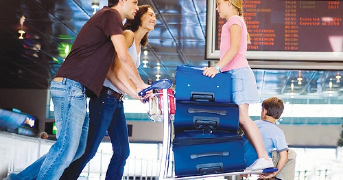 O familie cu doi copii lângă bagaje, într-un aeroport